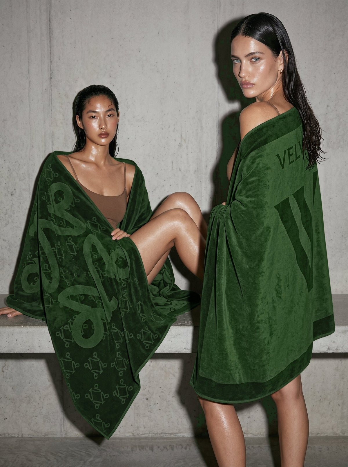 Two women seated on concrete, wrapped in VELVET Undergrowth towels