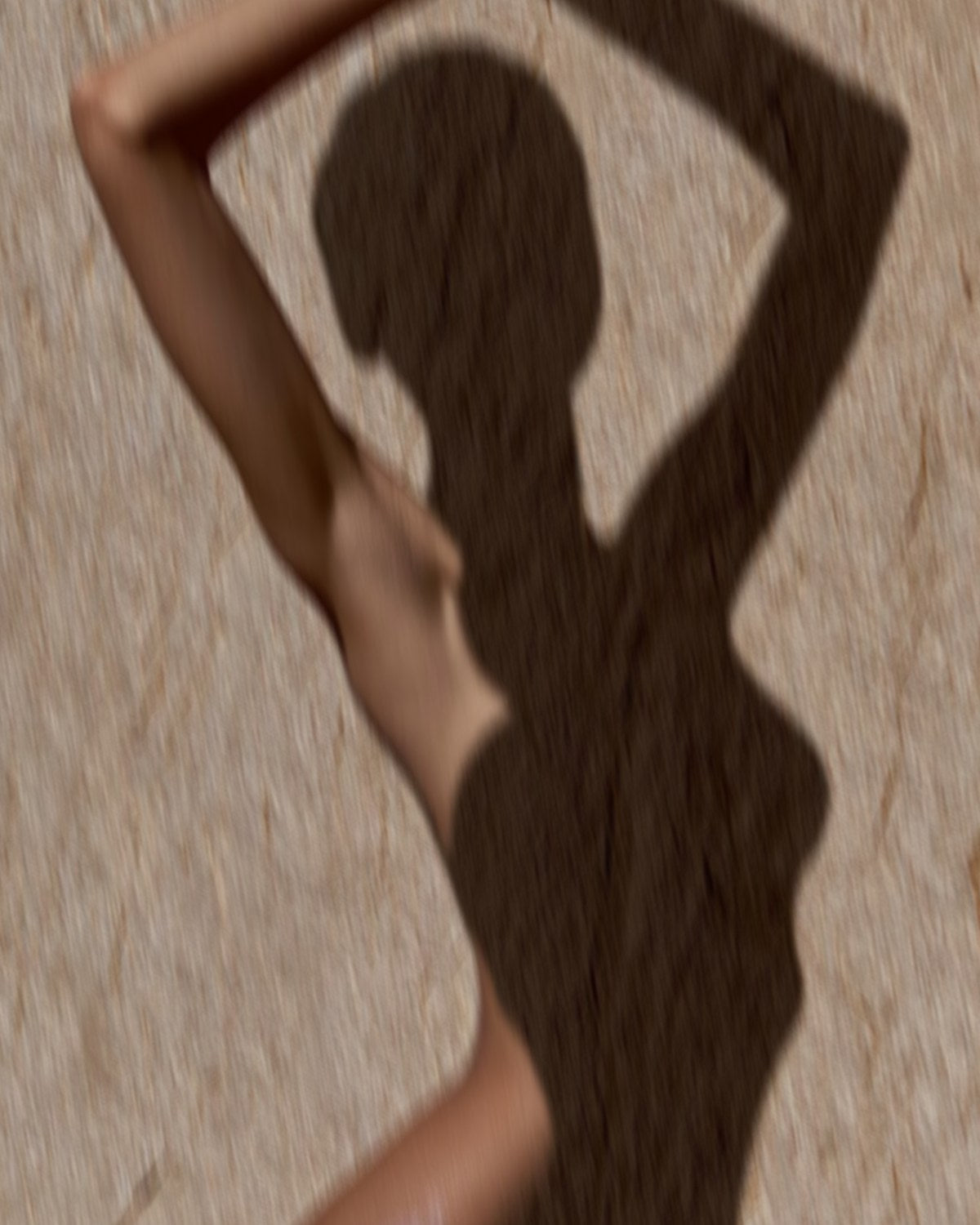 Shadow of a figure with arms raised on warm stone