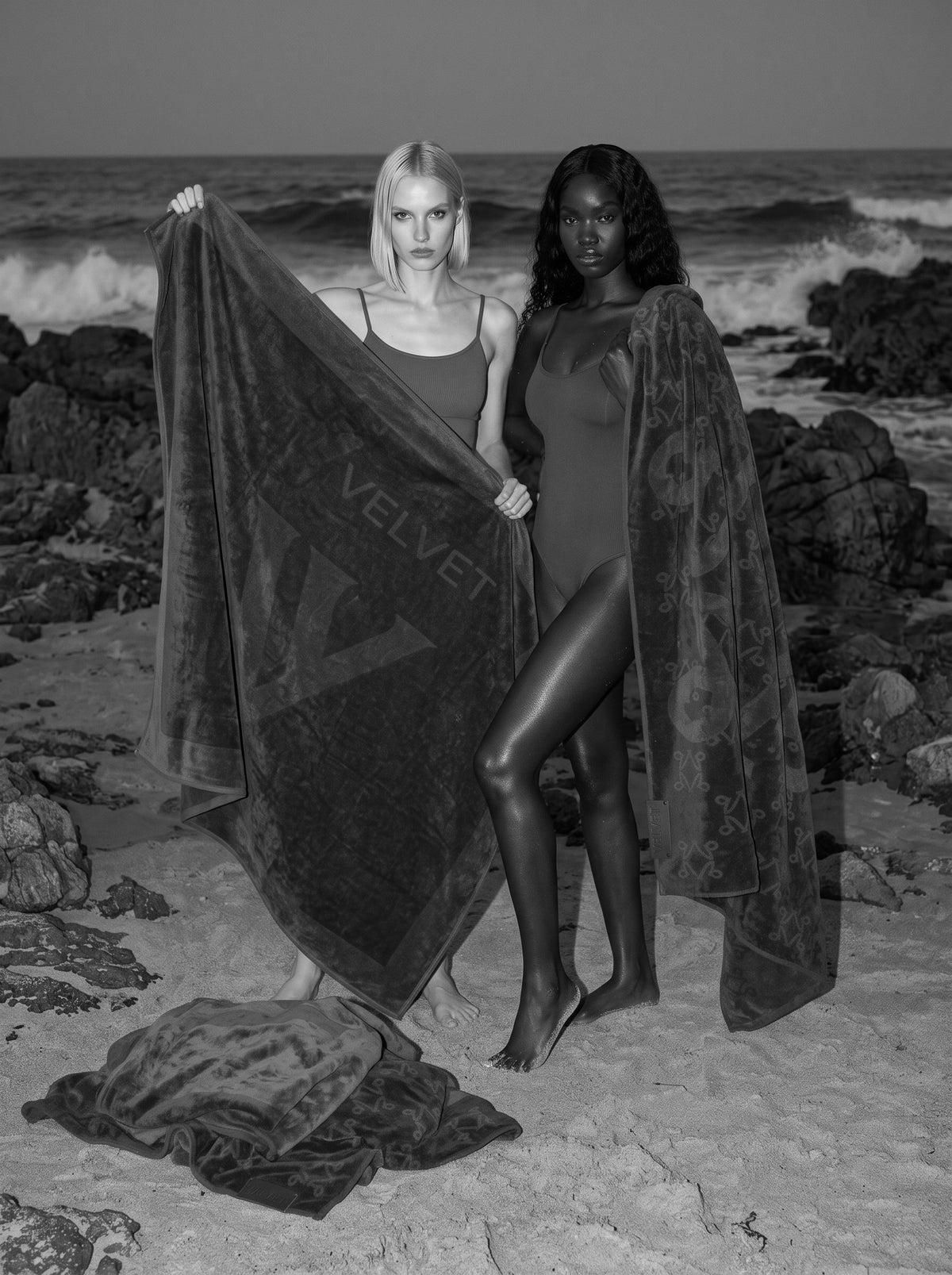 VELVET towels spread on a rocky shore at dusk, black and white